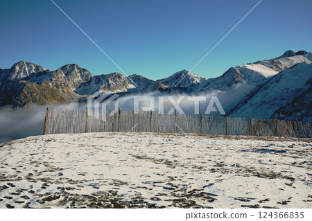Mountain ridge above the clouds. Fence in the mountain in the foggy morning. Mountain covered with first snow. View of mountains valley Pyrenees, Andorra, Europe 124366835