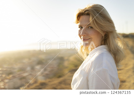 Blond woman enjoying golden hour light in scenic overlook Blond woman enjoying golden hour light in scenic overlook 124367135