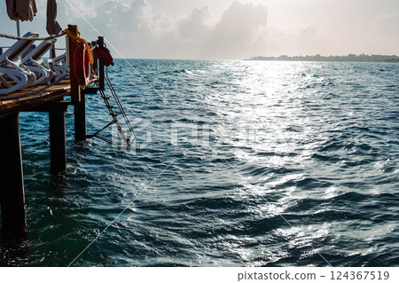 Picturesque seascape with a wooden pier extending into the turquoise waters of the ocean. Azure sky, sun glare on the water and play of light. Mediterranean Sea.Turkey Picturesque seascape with a wooden pier extending into the turquoise waters of the ocean. Azure sky, sun glare on the water and play of light. Mediterranean Sea.Turkey 124367519