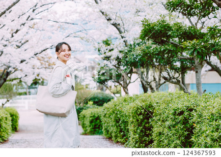 Young woman walking along cherry blossom trees 124367593