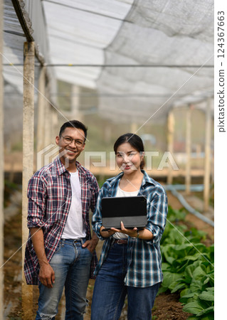 Confident farmers with digital tablet standing in organic farm. Smart farming concept 124367663