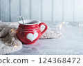 Red cup with white heart and decor details and bokeh copy space on light blurred background. 124368472