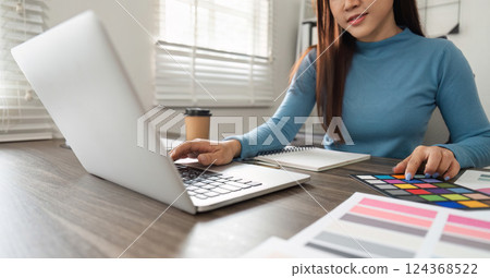 Creativity and Color Selection. A designer analyzing color palettes while working on a laptop in a modern workspace. 124368522