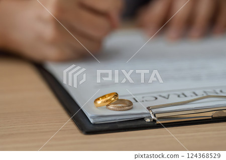 Divorce Proceedings and Acknowledgment. Wedding rings placed on top of legal documents signify a separation. Divorce Proceedings and Acknowledgment. Wedding rings placed on top of legal documents signify a separation. 124368529