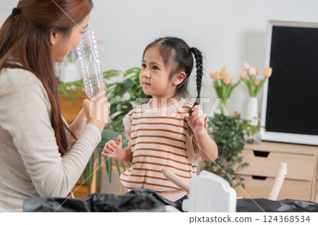 Recycling and Teaching. A mother and daughter engaged in a fun recycling session at home. 124368534