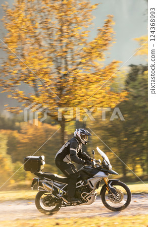 Motorcyclist rides through beautiful sunset landscape. 124368993