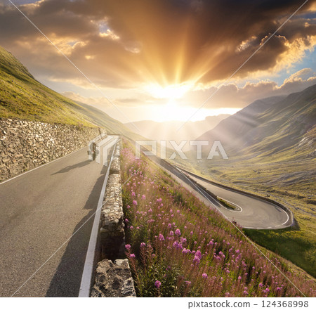 Motorcycle driver riding in beautiful alpine landscape in sunset light. 124368998