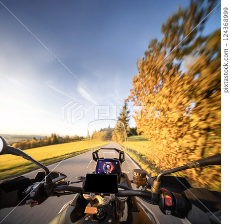 Detail of motorcycle handlebars. View from driver perspective, beautiful rural landscape in sunset light. Detail of motorcycle handlebars. View from driver perspective, beautiful rural landscape in sunset light. 124368999