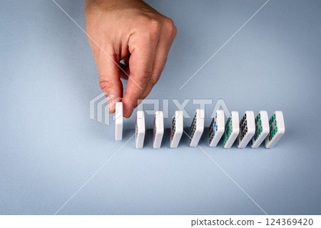 Hand carefully setting domino tile in a sequential line on a table 124369420