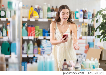 Young woman choosing household chemicals while makes video call Young woman choosing household chemicals while makes video call 124370179