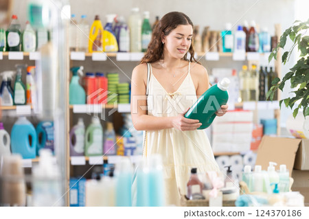 Girl choose liquid detergent in household shop Girl choose liquid detergent in household shop 124370186