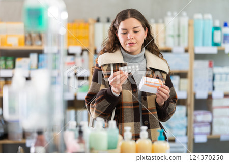 Young woman chooses pills at pharmacy 124370250