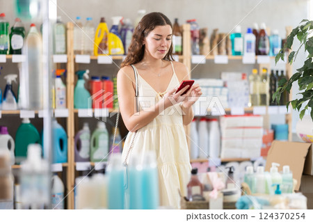 Girl store client looks at phone screen, reads shopping list 124370254