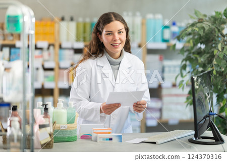 Female pharmacist reads prescription and enters the data into computer 124370316