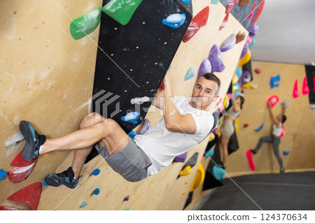 Man climbs steep artificial wall in sports complex and trains endurance 124370634