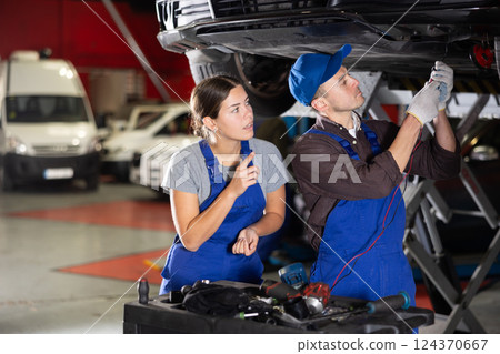 Guy and woman mechanics fix car wiring Guy and woman mechanics fix car wiring 124370667