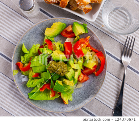 Plate contains portion of salad from fresh vegetables and pesto sauce. 124370671