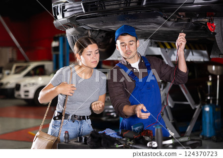 Guy mechanic checking woman client's car with measuring device 124370723