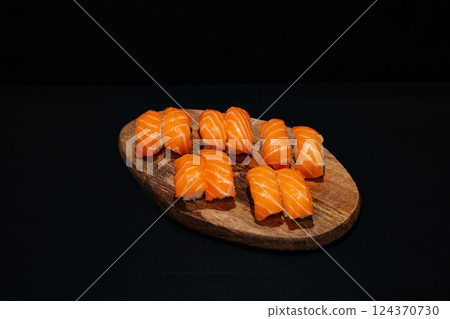 Creative minimalist display of Nigiri Sushi on a wooden platter against a dark backdrop, emphasizing vibrant colors and exquisite Japanese culinary art with a modern aesthetic. 124370730