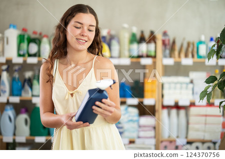 Girl choose kitchen cleaner spray in household shop Girl choose kitchen cleaner spray in household shop 124370756