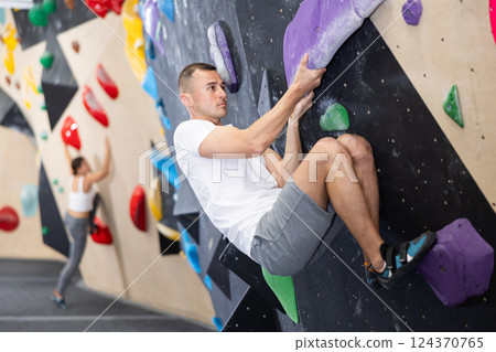 Man climbs steep artificial wall in sports complex and trains endurance 124370765