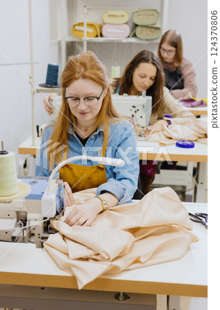 Three women seamstresses and fashion designers work in for sewing machines, clothing production. Three women seamstresses and fashion designers work in for sewing machines, clothing production. 124370806