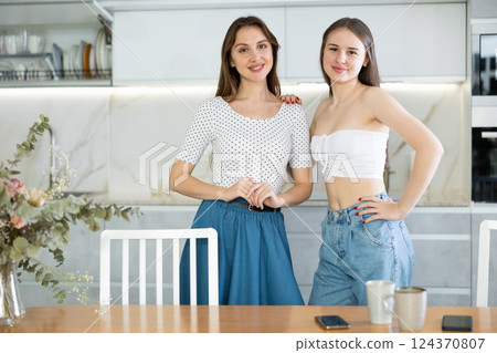 Happy middle-aged mother standing with her young daughter in the kitchen 124370807