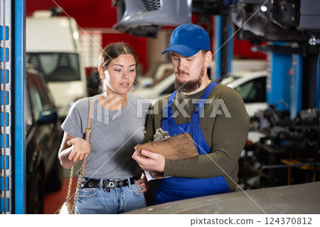 Mechanic guy signs agreement with young woman client Mechanic guy signs agreement with young woman client 124370812