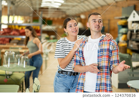 Spouses look for something in furniture store, searching for perfect item to complete patio Spouses look for something in furniture store, searching for perfect item to complete patio 124370816