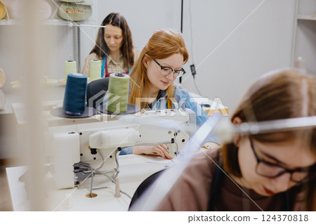 Three women seamstresses and fashion designers work in for sewing machines, clothing production. Three women seamstresses and fashion designers work in for sewing machines, clothing production. 124370818