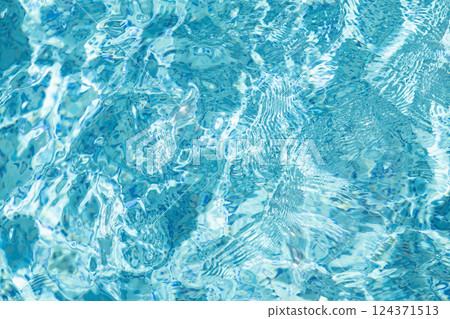 Transparent blue water in swimming pool with waves in sunlight. Abstract surface texture or nature background. Water surface 124371513