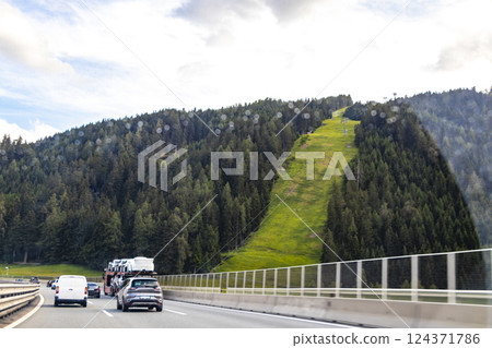 Mountain landscape green fields forest clouds highway road Tyrol Austria. 124371786