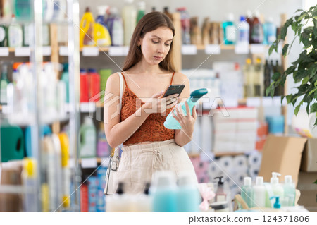 Young woman scanning bottle of glass cleaner in store Young woman scanning bottle of glass cleaner in store 124371806