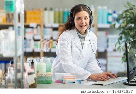 Female pharmacist in headphones with microphone consults patient on Internet 124371837