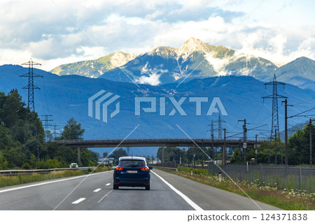 Mountain landscape green fields forest clouds highway road Vorarlberg Austria. 124371838