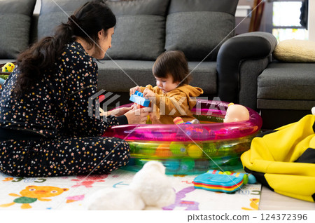 Cherished moments of playtime between a mother and her toddler in a cozy living room filled with colorful toys and joy Cherished moments of playtime between a mother and her toddler in a cozy living room filled with colorful toys and joy 124372396