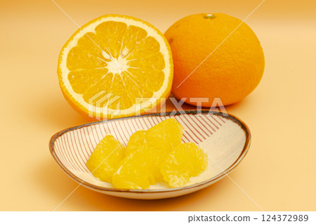 Stock photo of the cross section of a red summer mandarin orange and the peeled flesh on a small plate 124372989
