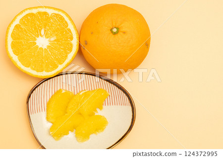 Stock photo of the cross section of a red summer mandarin orange and the peeled flesh on a small plate Stock photo of the cross section of a red summer mandarin orange and the peeled flesh on a small plate 124372995