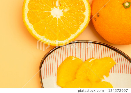 Stock photo of the cross section of a red summer mandarin orange and the peeled flesh on a small plate Stock photo of the cross section of a red summer mandarin orange and the peeled flesh on a small plate 124372997