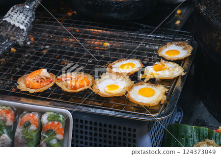 cooked traditional Vietnamese dish Banh Khot with shrimps and corn at Asian night market on the street in Vietnam in Asia cooked traditional Vietnamese dish Banh Khot with shrimps and corn at Asian night market on the street in Vietnam in Asia 124373049