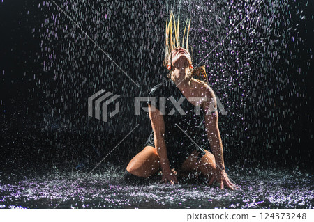 Contemporary woman dancer posing in rain water on black background. Female artist performer dancing with expression. Modern ballerina dancing in darkness. Passion dance in dark. Flexibility balance Contemporary woman dancer posing in rain water on black background. Female artist performer dancing with expression. Modern ballerina dancing in darkness. Passion dance in dark. Flexibility balance 124373248