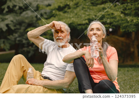 Senior man and woman with yoga mats sitting at park with bottles of water. Positive mature man and his elderly wife after fitness or yoga class in nature. Wellness and healthy lifestyle on retirement. Senior man and woman with yoga mats sitting at park with bottles of water. Positive mature man and his elderly wife after fitness or yoga class in nature. Wellness and healthy lifestyle on retirement. 124373395