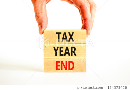 Tax year end symbol. Concept words Tax year end on beautiful wooden blocks. Beautiful white background. Businessman hand. Business tax year end concept. Copy space. Tax year end symbol. Concept words Tax year end on beautiful wooden blocks. Beautiful white background. Businessman hand. Business tax year end concept. Copy space. 124373426