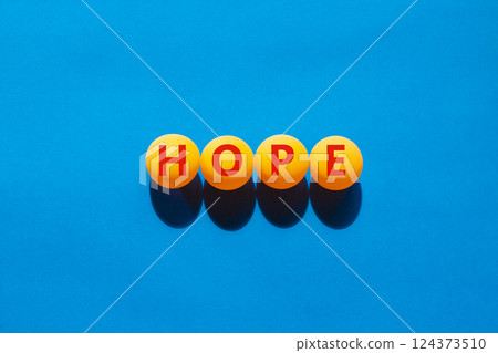 Hope symbol. Concept word Hope on beautiful yellow ping pong balls. Beautiful blue table blue background. Business, lifestyle, support and hope concept. Copy space. Hope symbol. Concept word Hope on beautiful yellow ping pong balls. Beautiful blue table blue background. Business, lifestyle, support and hope concept. Copy space. 124373510