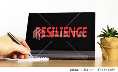 Resilience symbol. Concept word Resilience on beautiful black tablet. Beautiful wooden table white background. Businessman hand with pen. Business resilience concept. Copy space. 124373562