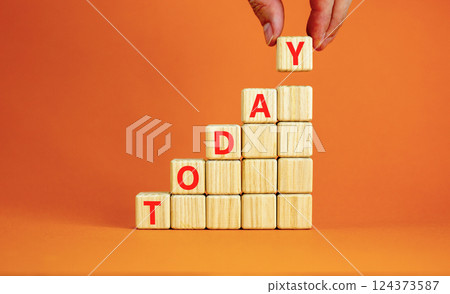 Today symbol. Concept word Today on beautiful wooden blocks. Beautiful orange table orange background. Businessman hand. Business lifestyle today concept. Copy space. 124373587