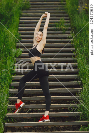 Pretty lady training in a summer city. Brunette doing yoga. Gitl in a sportsuit. Pretty lady training in a summer city. Brunette doing yoga. Gitl in a sportsuit. 124373659