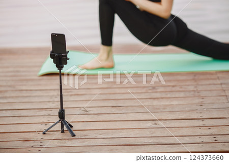 Pretty lady training in a summer park. Brunette doing yoga. Girl shoots a blog. 124373660