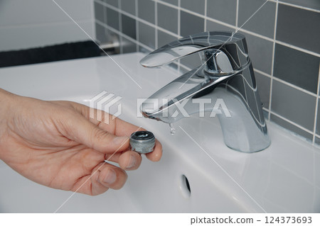 man have removed the aerator from a faucet 124373693