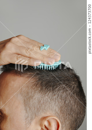 man combs his hair with a round scalp brush man combs his hair with a round scalp brush 124373700
